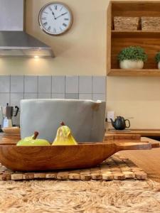Un cuenco de madera con peras en una encimera de cocina con un reloj. en A Destination To Delight!, en Ballarat