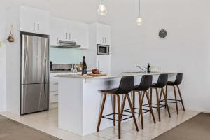 cocina blanca con nevera y taburetes en Stockyards 1, en Jindabyne