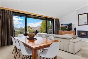 Una sala de estar con una mesa de madera y sillas blancas. en Stockyards 1, en Jindabyne