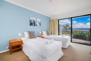 Un dormitorio con dos camas y una gran ventana. en Stockyards 1, en Jindabyne