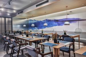 a restaurant with wooden tables and chairs and a painting on the wall at Pagoda Hotel Hangzhou West Lake Wulin - City Center and Family Friendly in Hangzhou