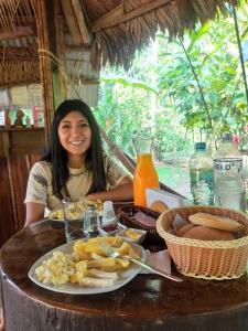 uma mulher sentada numa mesa com um prato de comida em Tronco Tambopata Adventure em Puerto Maldonado