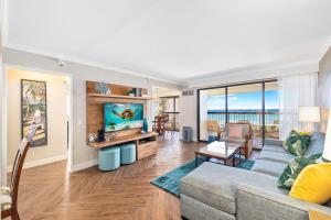 ein Wohnzimmer mit einem Sofa und einem TV in der Unterkunft Semprose Waikiki Beach Tower in Honolulu