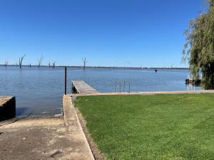 a view of a lake with a dock and grass at Waterside Mulwala in Mulwala