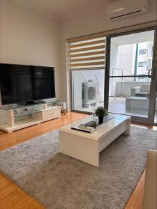 sala de estar con TV de pantalla plana grande en 2 On Trend Condo Near Crown 1br en Perth