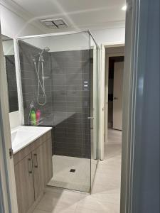 La salle de bains est pourvue d'une douche, d'un lavabo et d'une cabine de douche en verre. dans l'établissement 2 On Trend Condo Near Crown 1br, à Perth