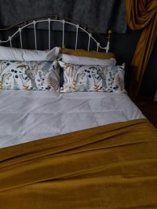 Una cama con sábanas blancas y almohadas. en Gadute Haven, en Pretoria