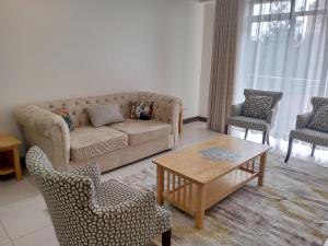 ein Wohnzimmer mit einem Sofa, Stühlen und einem Tisch in der Unterkunft Yohana Residences in Nairobi