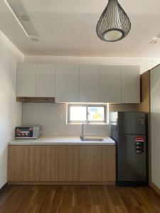 a kitchen with white cabinets and a black refrigerator at Tree Homestay in Da Nang