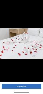 a white bed with red petals on it at Tree Homestay in Da Nang