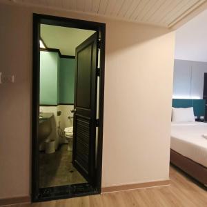 an open door to a bedroom with a bed and a toilet at Mayflower Grande Hotel Phitsanulok in Phitsanulok