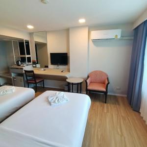 a hotel room with two beds and a desk at Mayflower Grande Hotel Phitsanulok in Phitsanulok