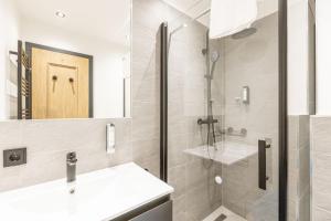 a bathroom with a shower and a sink and a mirror at Saalbach Suites by ALPS RESORTS in Saalbach-Hinterglemm +48 photos