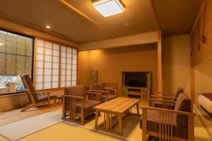 Habitación con sillas, mesa y TV. en Yukemuri no Yado Inazumi Onsen, en Yuzawa