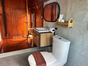 a bathroom with a toilet and a sink and a mirror at Bann Rai I Na in Phrae