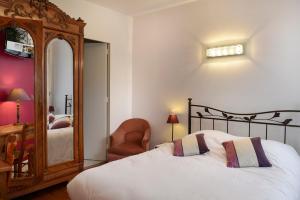 - une chambre avec un lit, un miroir et une chaise dans l'établissement Logis Manoir De La Giraudière, à Beaumont-en-Véron
