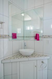 La salle de bains blanche est pourvue d'un lavabo et d'un miroir. dans l'établissement Adorable 1-bedroom-apartment 2 km from Eagle beach, à Palm-Eagle Beach