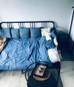 a bed with a blue blanket and a glass table at Viesu māja Virši in Stropi