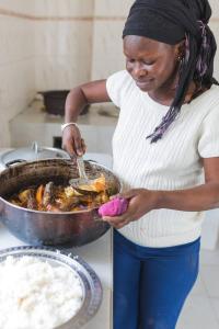 a woman preparing food in a pan in a kitchen at HomeVilla in Brusubi