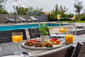 uma mesa com um prato de comida e copos de sumo de laranja em NEW! Villa Lukas with 44m2 pool in Makarska hinterland em Gornji Vinjani