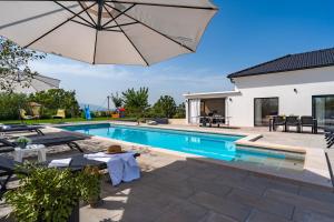 uma piscina com um guarda-sol ao lado de uma casa em NEW! Villa Lukas with 44m2 pool in Makarska hinterland em Gornji Vinjani