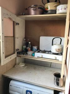 a kitchen with a stove and a microwave on a shelf at T7B hostel in Tbilisi City