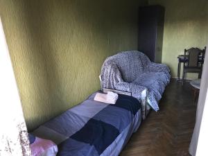 T7B hostel في تبليسي: غرفة بها كرسي وسرير مع بطانية