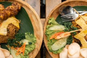 two plates of food with vegetables and meat on them at Bobocabin Madasari, Pangandaran in Bulakbenda