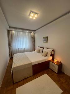a bedroom with a large bed and a window at SASE Apartment in Sarajevo