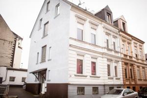a white building with a car parked in front of it at BIG Apartment bis 7 Personen in Solingen
