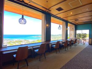 comedor con sillas y ventanas grandes en The Yuinchi Hotel Nanjo, en Nanjō