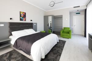 um quarto com uma cama grande e uma cadeira verde em Hotel Javu em Mamaia Nord – Năvodari