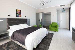 a bedroom with a large bed and a green chair at Hotel Javu in Mamaia Sat/Năvodari