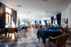 een restaurant met blauwe tafels en stoelen en mensen die er zitten bij Villaggio La Marée in Pisciotta