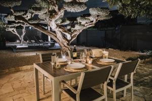 a table with plates and wine glasses and a tree at Oliveres3 in L'Ampolla