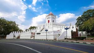 a white building with a tower on the side of a road at Alley & Pier in Bangkok