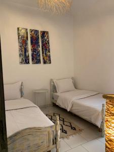 2 camas en una habitación con pinturas en la pared en cristal appart en Essaouira