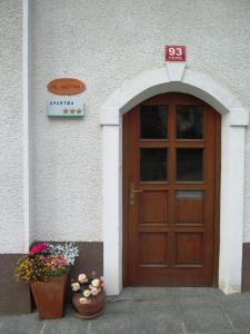 a wooden door on a building with two pots of flowers at Apartments Pr'Krštano in Kranjska Gora