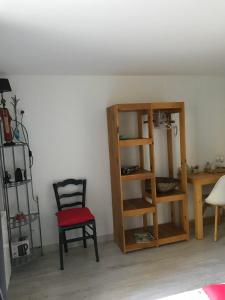 Habitación con silla y estante para libros en Chambre indépendante privée avec salle de bain, en La Chapelle-dʼAngillon