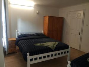 Schlafzimmer mit einem weißen Bett und einem Holzschrank in der Unterkunft Rahal Concord in London