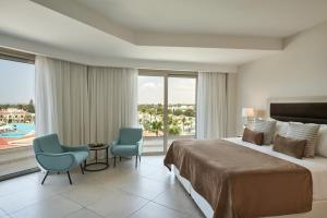 ein Hotelzimmer mit einem Bett und einem großen Fenster in der Unterkunft Atlantica Aeneas Resort in Ayia Napa