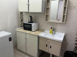 a small kitchen with a sink and a microwave at Al-Olaya Apartment in Umm Lujj