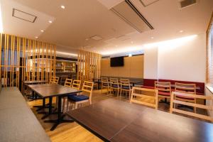 a dining room with tables and chairs and a tv at Business Hotel Ueno in Yamaguchi