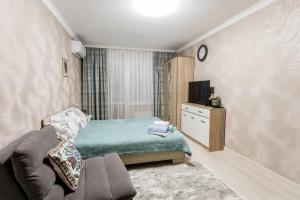 een slaapkamer met een bed, een bank en een tv bij Уютная квартира на Арбате in Alma-Ata