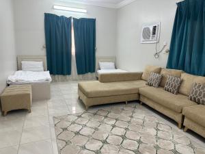 a living room with a couch and a bed at Al-Olaya Apartment in Umm Lujj