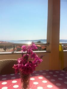 un vase rempli de fleurs roses assises sur une table dans l'établissement Apartments Juric, à Baška Voda