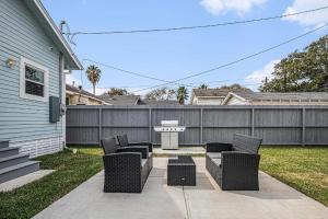 a patio with chairs and a table and a fence at Luxury Designer Villa by the Beach Bright Beautiful Brand New in Galveston