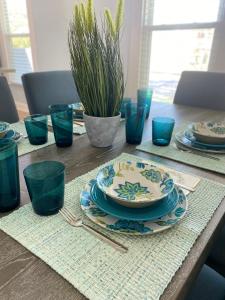 a wooden table with blue glasses and plates on it at Luxury Designer Villa by the Beach Bright Beautiful Brand New in Galveston