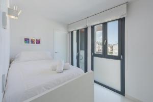 a white bedroom with a bed and a window at Ático Londres Derecha in Port de Pollensa