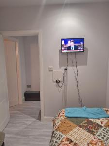 a room with a tv on a wall with a bed at Budget Single room only for one adult in Northolt